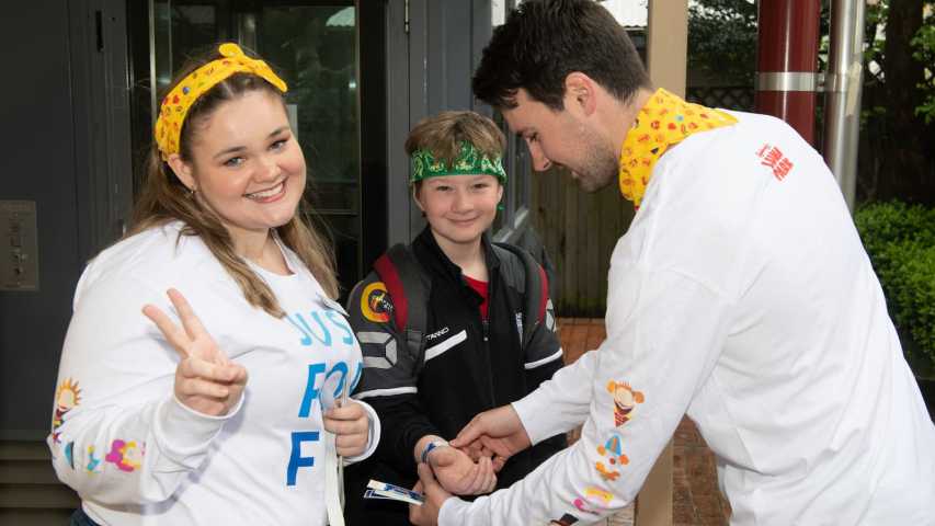 Young people affected by cancer putting on their wristband tickets