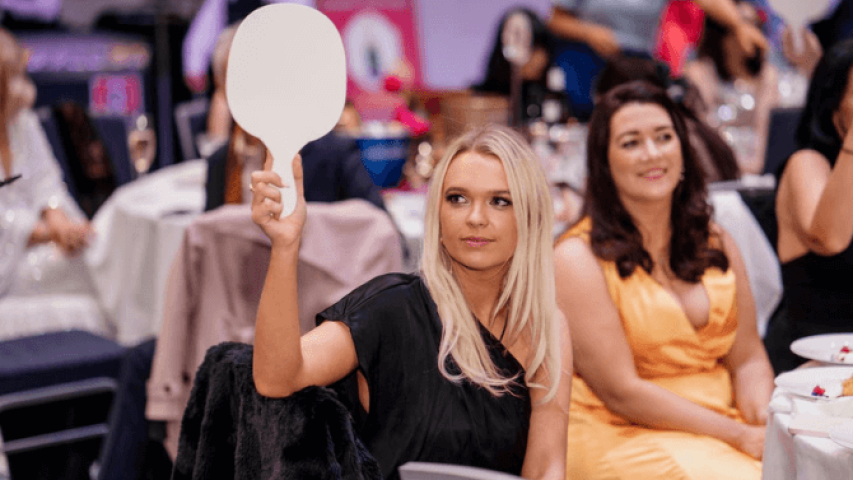 Samantha Stewart from Hilti is holding up a paddle at the gala fundraiser event