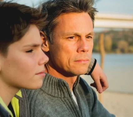 A solemn look on a father and sons face as a result of the impact of cancer